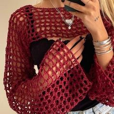 a woman is wearing a red crocheted shawl and holding a cell phone