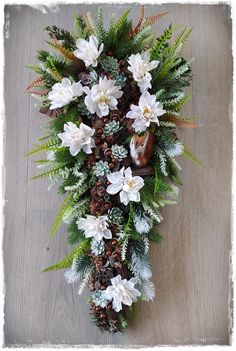 an overhead view of flowers and pine cones on a wooden floor with white snowflakes