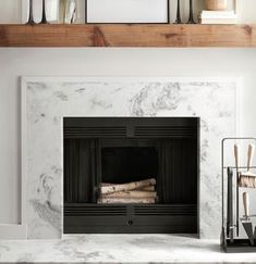 a fireplace with white marble surround and wood burning logs in the mantel above it