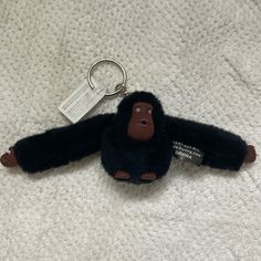 a stuffed monkey keychain with a tag hanging from it's side on a white blanket