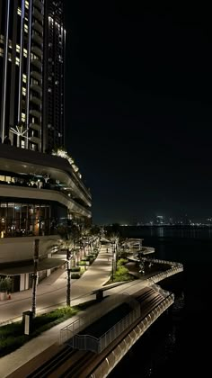 a night time view of a city with lights on and the ocean in the background