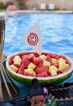 a bowl of watermelon and pineapple next to a pool