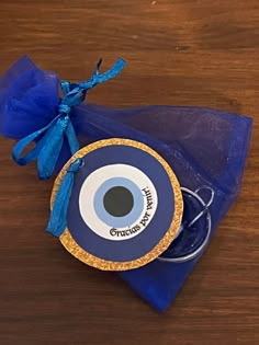 a blue bag with an eye on it sitting on top of a wooden table next to a pair of scissors