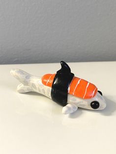 an orange and black toy fish sitting on top of a white table