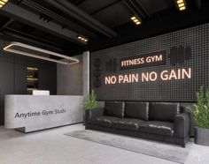 a black couch sitting in front of a sign that says gym no pain no gain