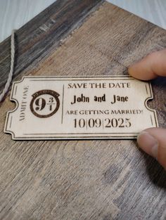 a person holding up a wooden save the date ticket on a table with string attached to it