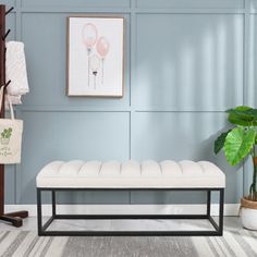 a white bench sitting on top of a rug in a living room next to a potted plant