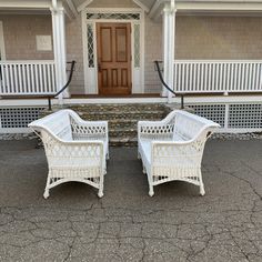 two white wicker chairs sitting in front of a house