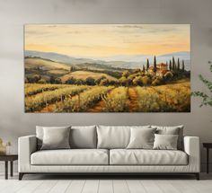 a living room with a white couch and painting on the wall above it that has an image of a countryside