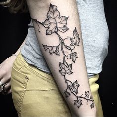 a woman with a tattoo on her arm has a flower and leaves design on it