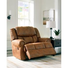 a reclining chair in a living room with a lamp on the side table and a window behind it