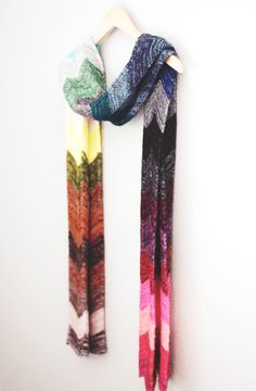 a multicolored scarf hanging on a wall next to a white coat hanger