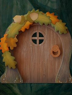 a wooden door with leaves on it and a hole in the front that has a wreath