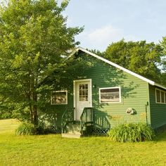 a small green house sitting on top of a lush green field