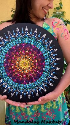 a woman is holding up a colorful painting