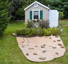 an outdoor play area in the backyard with rocks laid out on the ground and a shed behind it