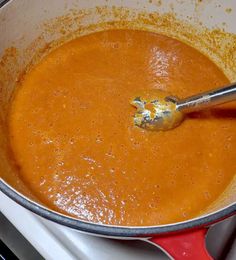 a large pot filled with soup and a ladle on top of the stovetop