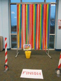 there is a sign on the floor in front of some colorful striped curtains and buckets