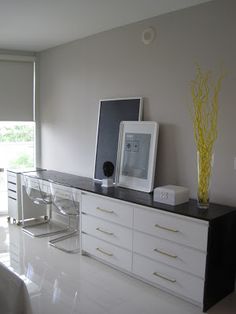 there is a white and black dresser in the living room with pictures on top of it