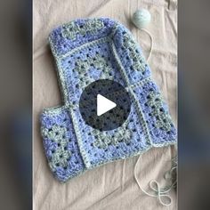 a crocheted blue and gray blanket with a video play button in the middle