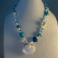 a white necklace with blue beads and a pearl on it's end, sitting on a mannequin