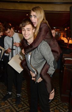 a man carrying a woman on his back in a restaurant with other people standing around