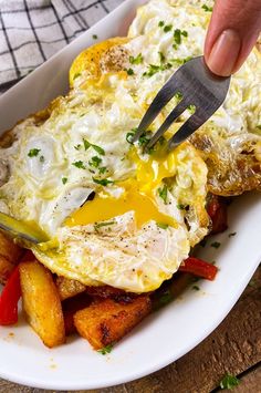 a person is cutting into an omelet with a knife and fork on a plate