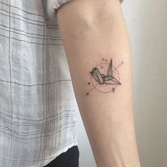 a woman's arm with a small origami tattoo on it