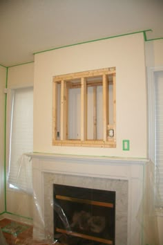 an unfinished fireplace in a living room with no one around it and the window frame is being installed