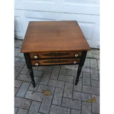 a small wooden table sitting on top of a brick floor next to a white door