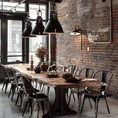 an industrial style dining room with exposed brick walls and large wooden table surrounded by black chairs