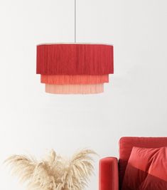 a living room with a red couch, chair and lamp hanging from the ceiling over it