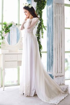 a woman in a white wedding dress standing next to a mirror