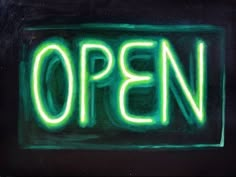 an open sign lit up with neon green lights in the dark, on a black background