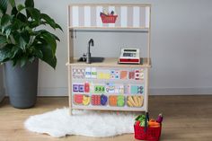 a toy kitchen with toys on the floor and a potted plant next to it