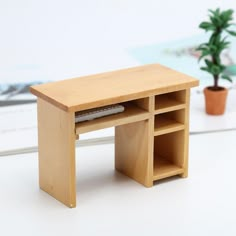 a small wooden desk with shelves and a potted plant next to it on a white surface