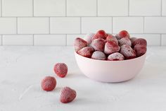 a white bowl filled with frozen strawberries on top of a counter