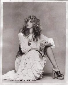 an old photo of a woman sitting on the ground with her legs crossed and wearing high heels