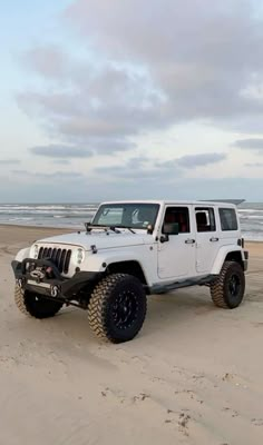 a white jeep parked on top of a sandy beach