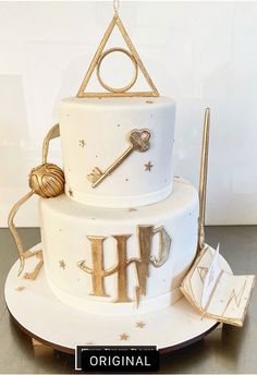 a three tiered cake decorated with harry potter symbols and wands is on display