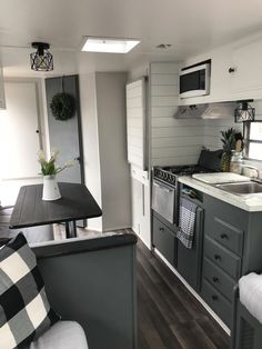 a kitchen and dining area in a mobile home with wood flooring, white walls and gray cabinets