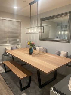 a dining room table with benches in front of it and a mirror on the wall