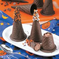 three chocolate cones with sprinkles are on a plate