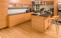 a modern kitchen with wooden cabinets and black counter tops, along with bar stools