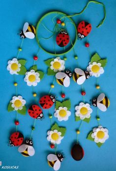 a group of ladybugs and daisies hanging from strings on a blue background