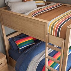 a wooden bunk bed with striped sheets and pillows