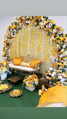 a decorated stage with yellow and white flowers on the wall, an open couch and several other decorations