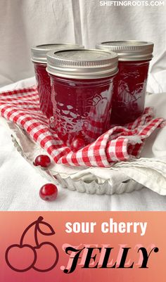 three jars of sour cherry jelly sitting on top of a white cloth with cherries