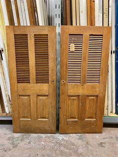 two wooden doors sitting next to each other in front of a wall full of books