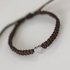 This bracelet is made of dark brown waterproof rope and a silver plated heart charm. Brown Bracelet With Lobster Clasp As Gift, Adjustable Brown Jewelry With Heart Charm, Brown Adjustable Heart Bracelet, Adjustable Heart Shaped Brown Bracelet, Adjustable Brown Heart-shaped Bracelet, Adjustable Brown Bracelet With Lobster Clasp, Heart-shaped Bracelet With Adjustable Cord As Gift, Adjustable Heart-shaped Brown Bracelet, Adjustable Hand-strung Brown Leather Bracelet